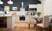 Hiddenhus - large open-plan kitchen with natural shaker-style cabinetry set against a contrasting midnight blue feature wall
