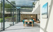 Blackhouse Forest Estate - the stunning glass atrium with dining table and armchairs beyond