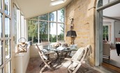 Honeystone House - garden room with plentiful natural light and seating for four round a glass dining table