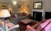 Wark Farmhouse - the drawing room with comfortable seating set around the wood burning stove