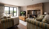 Brockmill Farmhouse - sitting room with large comfortable sofas, wood-burning stove and patio doors