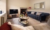Birch Cottage - sitting room with large inky blue Chesterfield sofa and cosy log burner