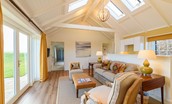 Fenton Lodge - open-plan living area with double height ceiling, French doors leading outside, sofa and two armchairs